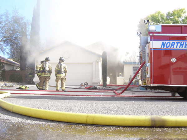 A residential house fire with heavy smoke still visible. At this fire, multiple hand lines were used to control the blaze and a Rapid Intervention Crew is seen standing by if called upon by interior crews..