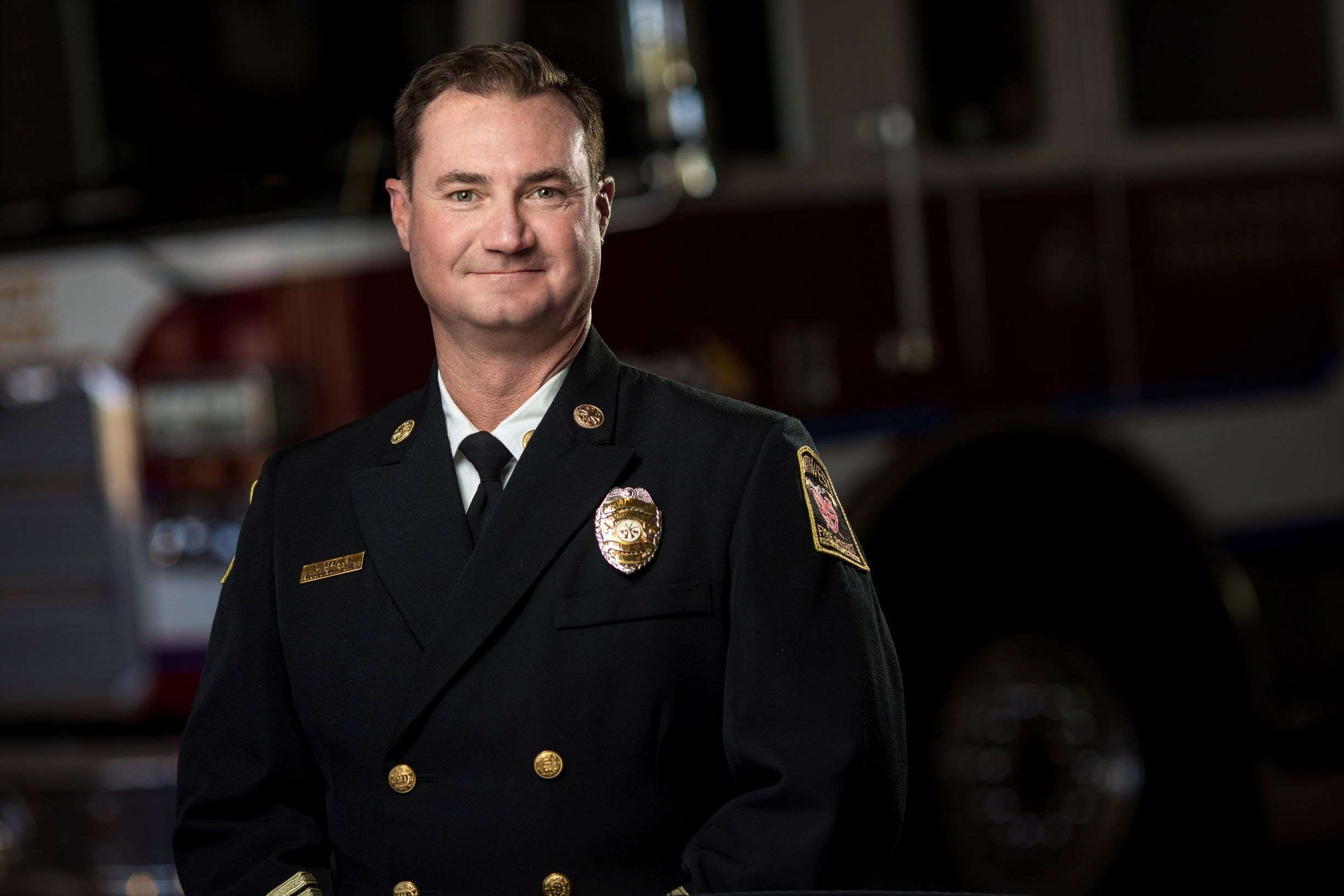 Chief Bradley in full dress uniform in front of a ladder truck.